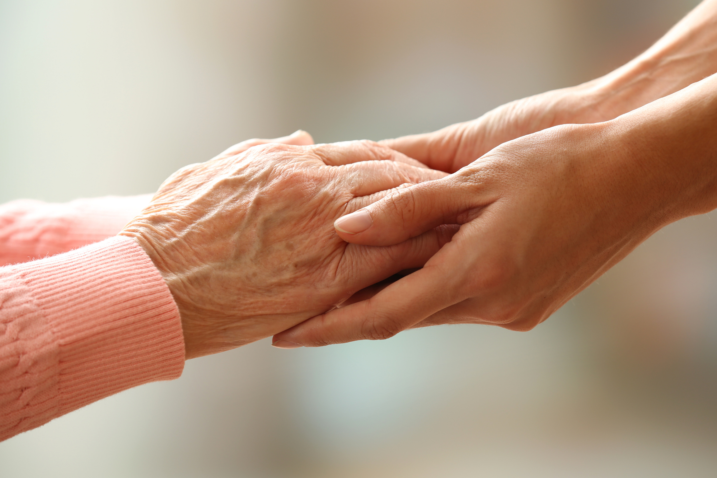 Old and Young People Holding Hands on Light Background, Closeup